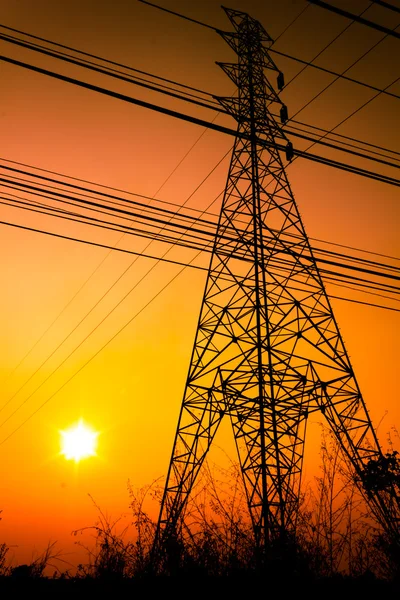 Högspänning power pole mitten av ett majsfält med orange himmel — Stockfoto