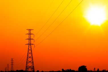 yüksek gerilim güç pole ortasında turuncu gökyüzü ile bir mısır tarlası