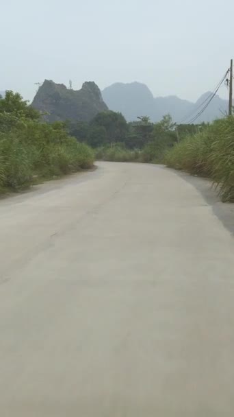 モータースクーターに乗るPovニンビン ベトナム農村部の田舎道 背景に山の石灰岩カルスト かすんで曇りの日 縦横比 — ストック動画