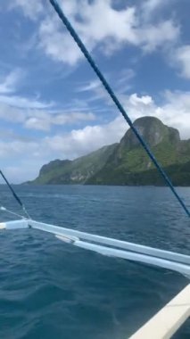 El Nido Filipinler adası tekneyle gezintiye çıkmak mavi su ve kireçtaşı karst manzaralı arka planda.