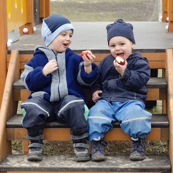 Bambini che mangiano mele al parco giochi . — Foto Stock