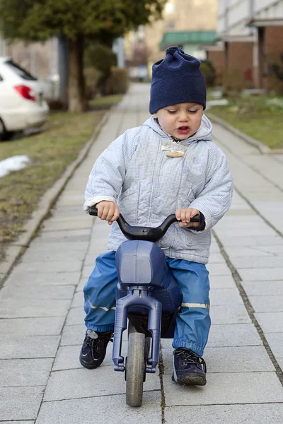 Kind met een stuk speelgoed fiets — Stockfoto