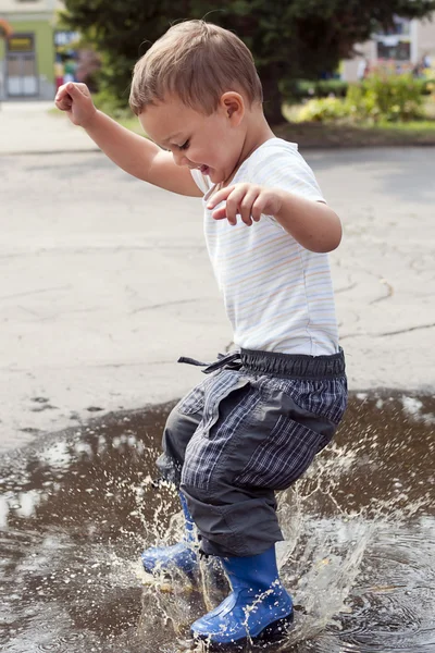 Child jumping in puddle — Stock Photo, Image