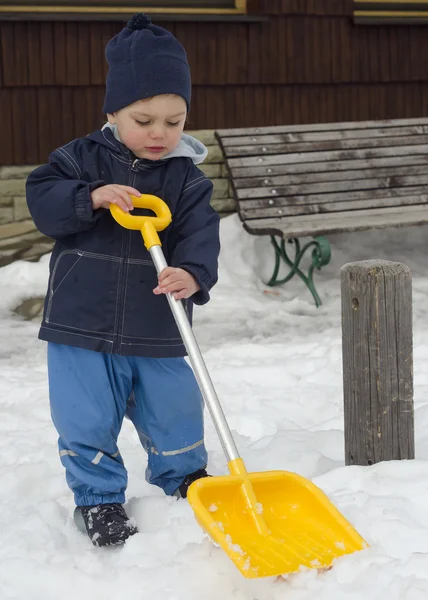Winter child with snow shovel — Stock Photo, Image