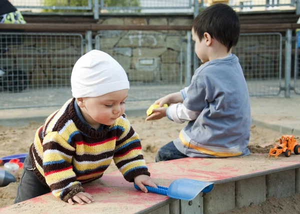 Дети играют с песком на детской площадке — стоковое фото
