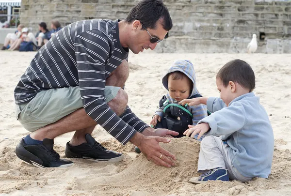 Pai e crianças construindo castelo de areia — Fotografia de Stock