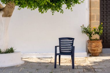 Evin önündeki bir ağacın altındaki verandada plastik sandalye, Akdeniz kasabasında ya da köyde tipik bir sahne, Lindos, Rhodos