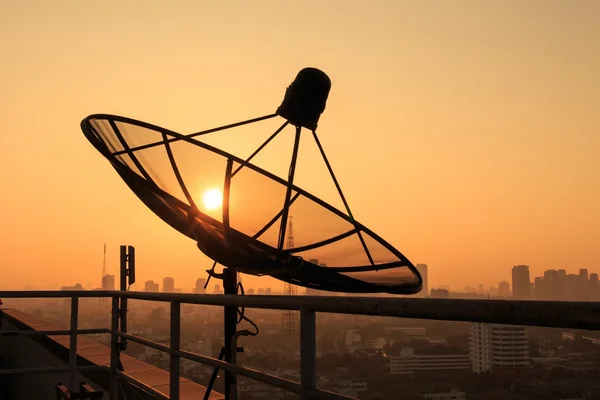日出时屋顶上的碟型卫星天线. — 图库照片