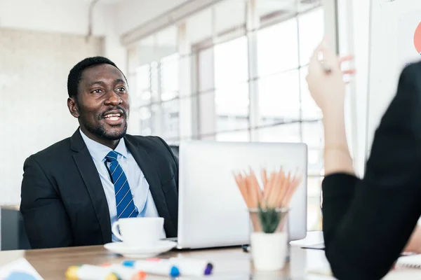 Afrikalı işadamı bir iş grubu toplantısında geçen yılki gözden geçirme ve ofiste yeni bir iş planı hakkındaki görüşünü paylaşıyor. Çeşitli uluslardan iş adamları.