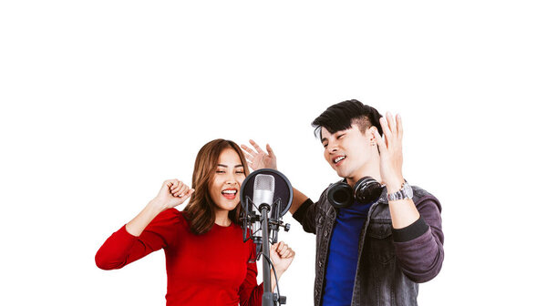 Pretty Asian female and male singers recording songs by using a studio microphone and pop shield on the microphone with passion in music recording studio white background. Duet session.