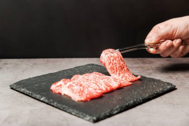 Premium Nadir Dilimler Wagyu A5 bifteği. Yüksek mermer dokuya sahip. Taş tabaktaki el ile bbq maşasıyla toplanıyor. Yakiniku, Sukiyaki ve Shabu 'ya hizmet etmiş. Kopyalama alanı olan resim.