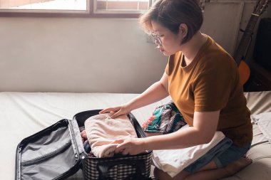 Bir kadın seçilmiş eşyalardan oluşan giysileri düzgünce katladı ve onları bagajın içine koydu. Kaçış tatiline gitmek için bavulumu topluyorum. Kıyafetlere odaklan..