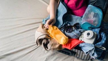 Güneş gözlüğü, polaroid kamera, kozmetik çanta ve küçük çanta gibi dağınık eşyaları kapat ve bagajdaki her şeyi mücadele ederek sığdırmaya çalış. Kaçış tatiline gitmek için bavul hazırlıyorum..