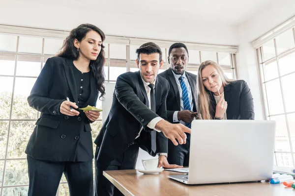 Kafkasyalı meslektaşlarının arasında duran Afrikalı işadamları bir iç iş gurubu toplantısında dizüstü bilgisayarlarına bakıyorlar. İş adamlarının işbirliği çeşitliliği.