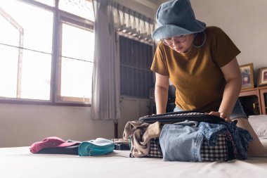 Asyalı kadın bagajdaki her şeyi boğuşan güneş gözlüğü, polaroid kamera, kozmetik çanta ve küçük çanta gibi eşyalarla doldurmaya çalışıyor. Kaçış tatiline gitmek için bavul hazırlıyorum..