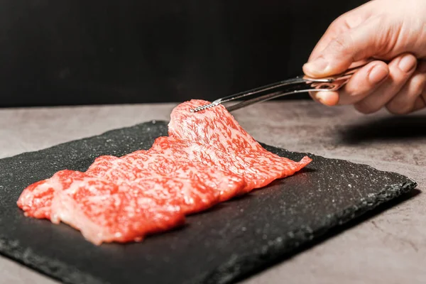Premium Nadir Dilimler Wagyu A5 bifteği. Yüksek mermer dokuya sahip. Taş tabaktaki el ile bbq maşasıyla toplanıyor. Yakiniku, Sukiyaki ve Shabu 'ya hizmet etmiş. Kopyalama alanı olan resim.