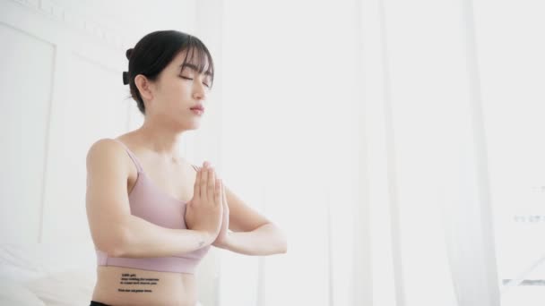 年轻迷人的亚洲女子微笑着 紧闭双眼练习瑜伽 做阿达哈 帕迪亚马纳纳运动 用半莲花式冥想 带着惊艳的神态 4K实时视频 — 图库视频影像