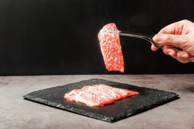Premium Nadir Dilimler Wagyu A5 bifteği. Yüksek mermer dokuya sahip. Taş tabaktaki el ile bbq maşasıyla toplanıyor. Yakiniku, Sukiyaki ve Shabu 'ya hizmet etmiş. Kopyalama alanı olan resim.