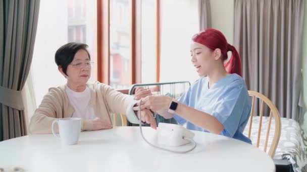 护士用自动血压监测器对成熟的亚洲老年妇女进行血压测量 照顾者在家里探访 家庭保健和疗养院概念 实时4K视频 — 图库视频影像