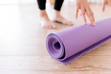 Spor kıyafetleri giymiş, su şişesiyle yoga minderi saran ve yogaya hazırlanan genç bir kadının görüntüsü. Evde ya da yoga stüdyosunda çalışıyorum. Sağlıklı alışkanlıklar, formda kalma, kilo verme kavramları.