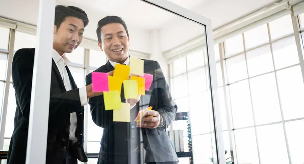 成功したアジアのビジネスマンのチームワークのグループ 新しいアイデアのためのガラスの壁に粘着性のある紙のメモとのブレインストーミング テクノロジースタートアップオフィスでのビジネスにアジャイル手法を活用 — ストック写真