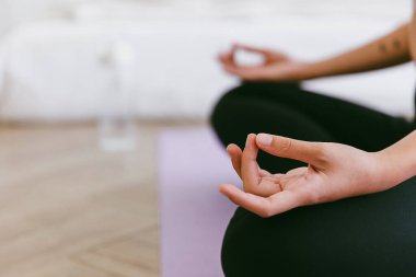 Sportif Asyalı kadının yoga minderinde yoga yaptığı meditasyon elini kapat Ardha Padmasana egzersizi yap, Yarım Lotus pozu ver, evde çalış..