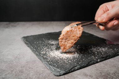 Orta nadir bulunan yüksek mermer sığır filetosu A5 Wagyu. BBQ maşasıyla toplanmış ve siyah taş bir tabağa tuz batırılmış. Yakiniku 'ya hizmet ettim..