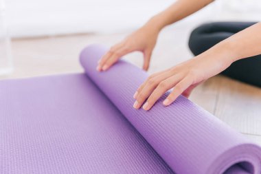 Yoga yapmaya hazırlanan yoga minderini çeviren kadının ellerini kapatın. Evde ya da yoga stüdyosunda çalışıyorum. Sağlıklı alışkanlıklar, formda kalma, kilo verme kavramları.
