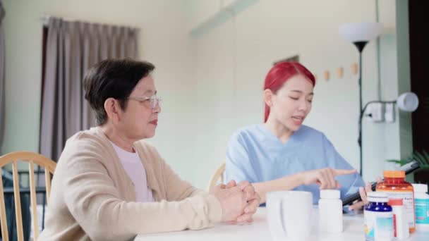 亚洲妇女在用药前 抱着药瓶护理 并向亚洲老年妇女提供信息 照顾者在家里探访 家庭保健概念 4K慢动作视频 — 图库视频影像