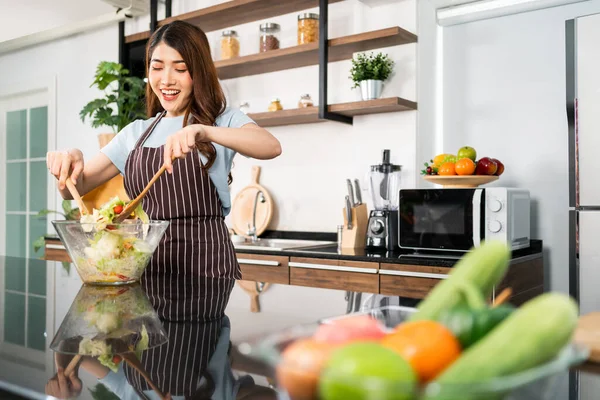 Joyeux Asiatique Femme Portant Tablier Jeter Salade Végétarienne Avec Spatules — Photo