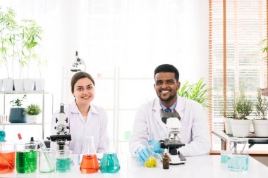 Çeşitli bilim adamlarının portreleri gülümsüyor ve araştırma laboratuarındaki kameraya bakıyor. Laboratuvarda mikroskop ve kimyasal sıvıyla çalışan bir grup kimya öğrencisi..