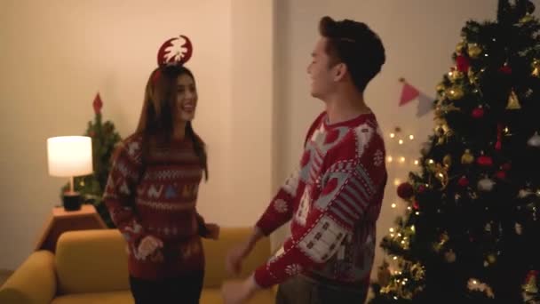 平安夜 一对身穿毛衣的快乐的亚洲夫妇在自家客厅的私人聚会上共舞 — 图库视频影像