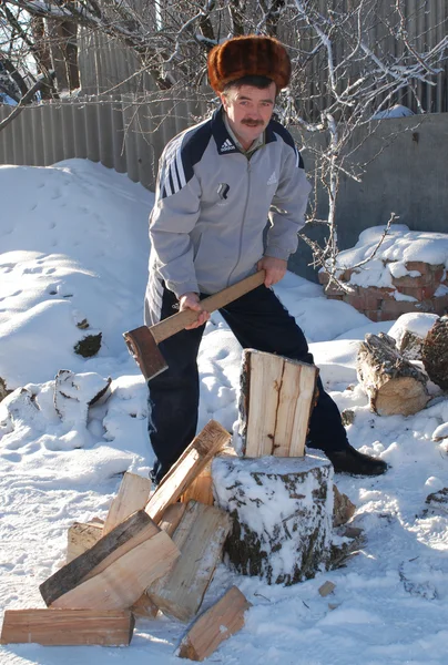 男子在冬天刀砍木头 — 图库照片