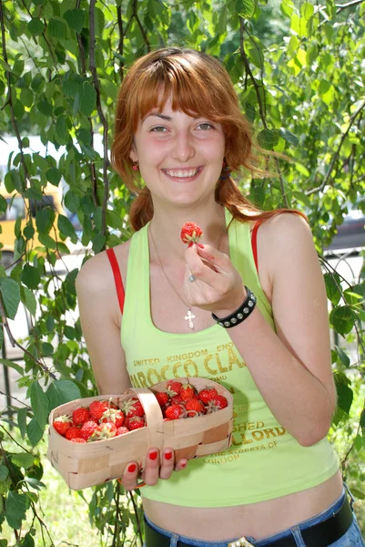 Mädchen essen Erdbeeren mit einem Korb Stockbild