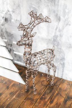 Beyaz ahşap bir Noel ağacının yakınındaki bir odada arka planda ışık tutan bir Noel geyiği.