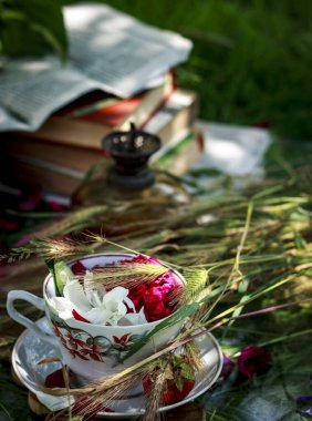 Yaz kompozisyonu, şakayık yapraklı bardak, yağ lambası, eski kitaplar, güneşli bir günde buğday.
