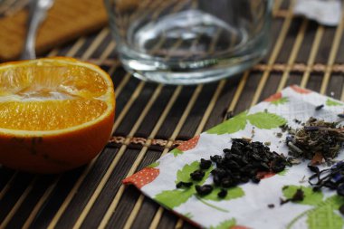 İki portakal dilimi, cam bardak, siyah ve yeşil çay, bambu tahtasında peçete.