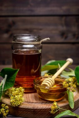 Kavanoz ve ıhlamur balı bal ve bal için sopa ve ahşap bir masada taze ıhlamur çiçeği..
