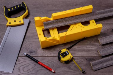 Yapı aracı - miter testeresi lamine bir zemin, kalem ve metre üzerinde miter kutusu ile.