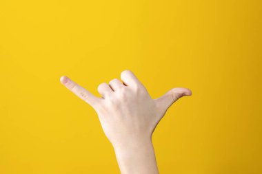 Sarı arka planda çağrı jesti ile el gösteren kişinin kırpılmış görüntüsü 