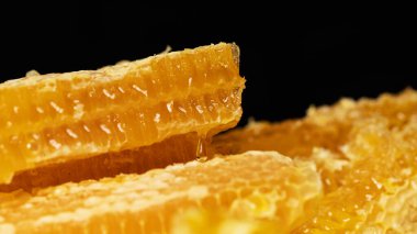 Siyah arka planda bal peteği kesimi. Bal peteği kesimine bir damla bal. Alternatif tıp, soğuk algınlığı ve grip için doğal ev tedavisi.