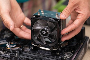 Engineer man installing aluminum heat sink install at computer circuit board for cooling chips. Air cooling system of desktop computer processor. Russia, 17.08.2021