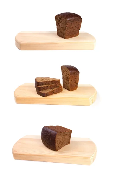 Um conjunto de pão marrom em uma tábua de corte — Fotografia de Stock