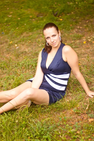 Ein junges Mädchen sitzt auf einem Rasen — Stockfoto