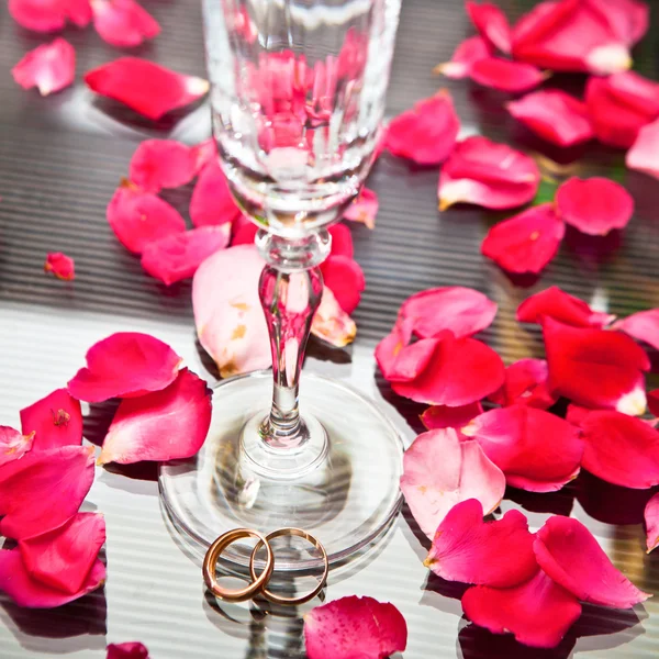 Wedding rings at the base of wine glass — Stock Photo, Image