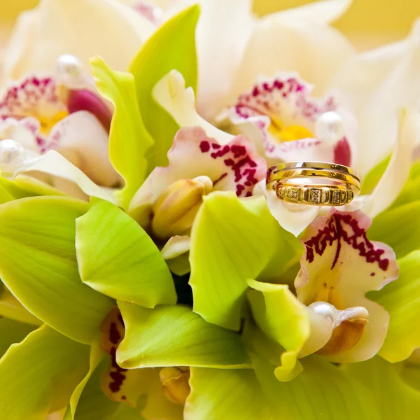 Wedding rings on a bouquet of orchids — Stock Photo, Image