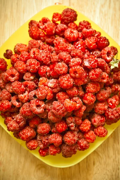 Himbeeren auf einem gelben Teller — Stockfoto