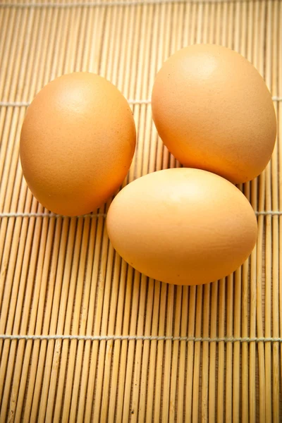 Chicken eggs on a wooden mat — Stock Photo, Image