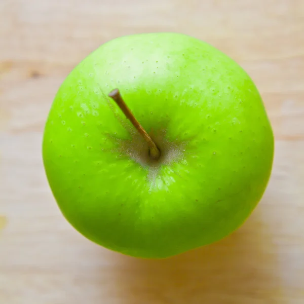 Grüner Apfel auf einem hölzernen Hintergrund — Stockfoto
