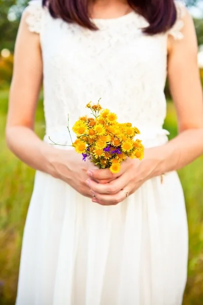 Bouquet of wild flowers in the bride's hands — Stock Photo, Image